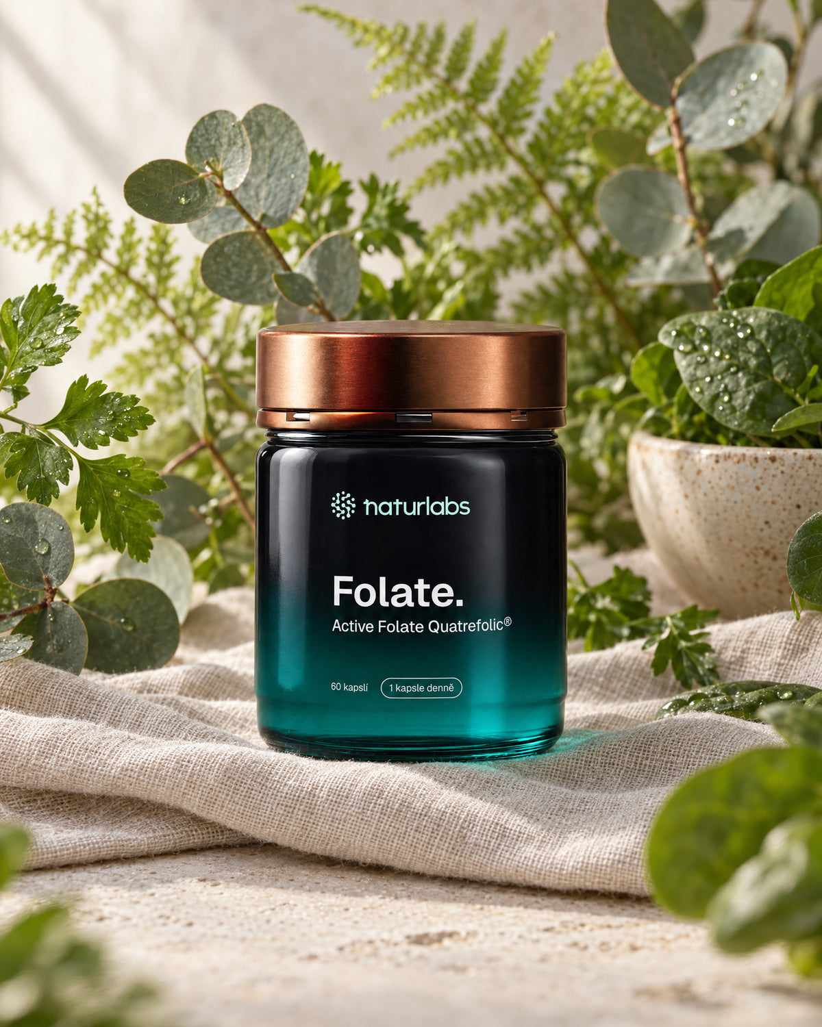 Bioaktivní folát Quatrefolic® NaturLabs na lněné látce mezi kapradím, eukalyptem a čerstvou zelení v měkkém denním světle